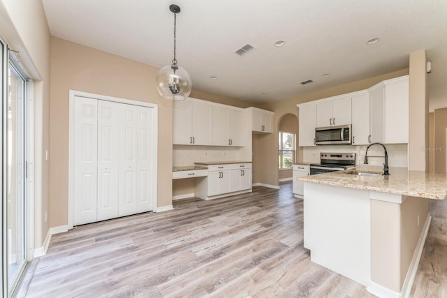 kitchen featuring stainless steel appliances, sink, pendant lighting, white cabinetry, and light hardwood / wood-style floors