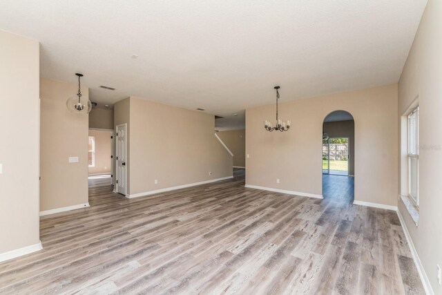 1344 Holly Glen Run, Apopka, FL 32703 - empty room featuring a chandelier, light wood-type flooring, arched walkways, and baseboards