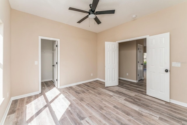 1344 Holly Glen Run, Apopka, FL 32703 - unfurnished bedroom featuring light wood-style flooring, baseboards, a ceiling fan, a walk in closet, and a closet