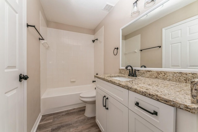 full bathroom featuring toilet, hardwood / wood-style floors, tiled shower / bath combo, and vanity