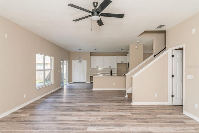 unfurnished living room with light hardwood / wood-style floors, a textured ceiling, and ceiling fan