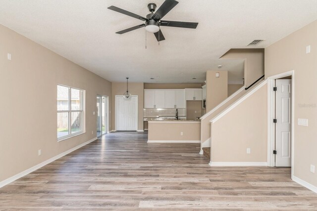 1344 Holly Glen Run, Apopka, FL 32703 - unfurnished living room with light wood finished floors, ceiling fan, baseboards, and a sink