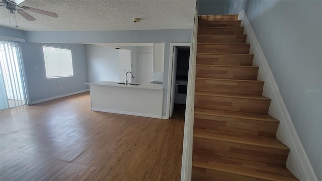 stairs with hardwood / wood-style floors, ceiling fan, sink, and a textured ceiling