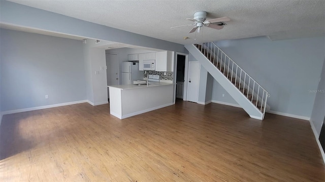 unfurnished living room with hardwood / wood-style floors, a textured ceiling, sink, and ceiling fan