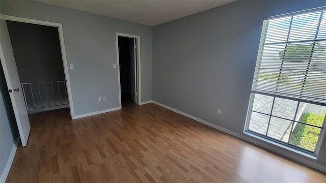 unfurnished bedroom featuring a closet, a walk in closet, and hardwood / wood-style floors