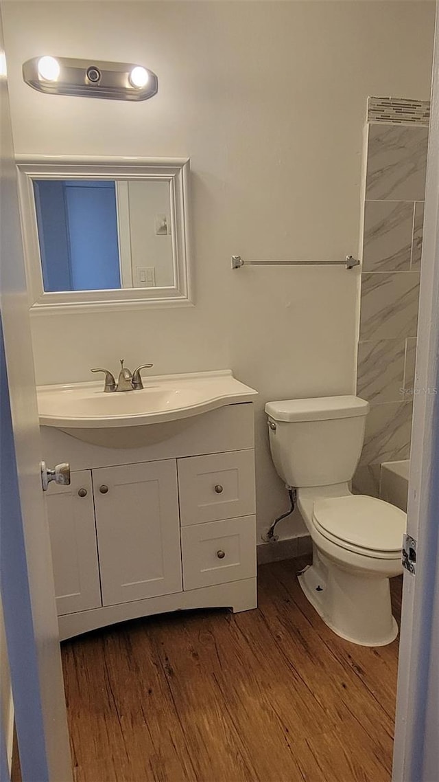 bathroom with vanity, tiled shower, hardwood / wood-style flooring, and toilet