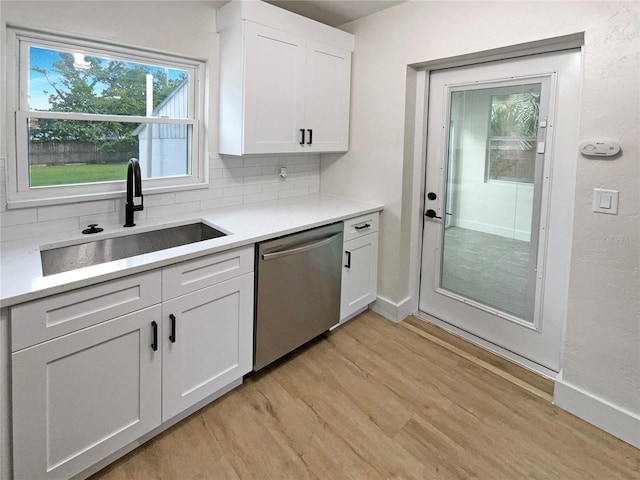 kitchen featuring light hardwood / wood-style floors, white cabinetry, stainless steel dishwasher, and sink