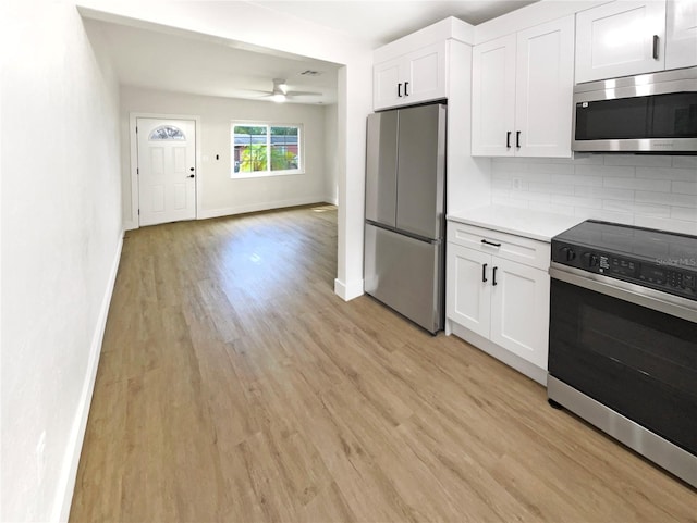 kitchen with white cabinets, ceiling fan, appliances with stainless steel finishes, backsplash, and light hardwood / wood-style flooring