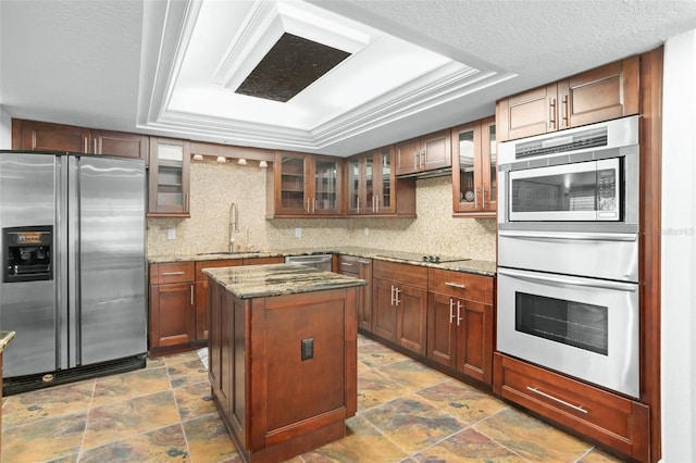 kitchen featuring tasteful backsplash, dark stone counters, stainless steel appliances, sink, and a kitchen island