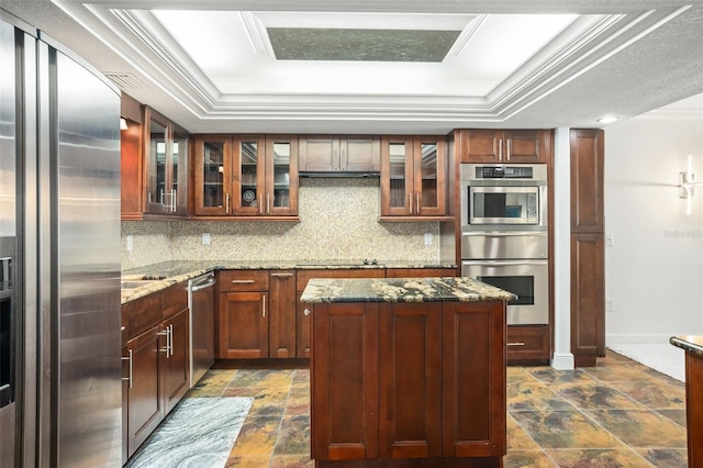 8984 Houston Pl Unit 103, Orlando, FL 32819 - kitchen with appliances with stainless steel finishes, a tray ceiling, stone finish flooring, a warming drawer, and backsplash