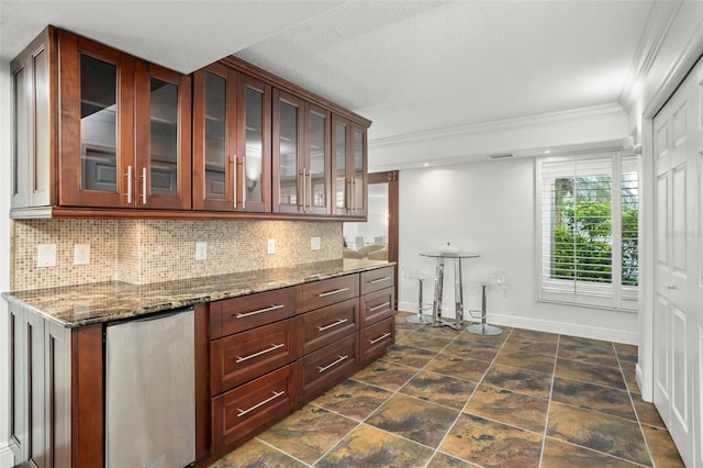 8984 Houston Pl Unit 103, Orlando, FL 32819 - kitchen featuring crown molding, tasteful backsplash, dark stone counters, glass insert cabinets, and fridge