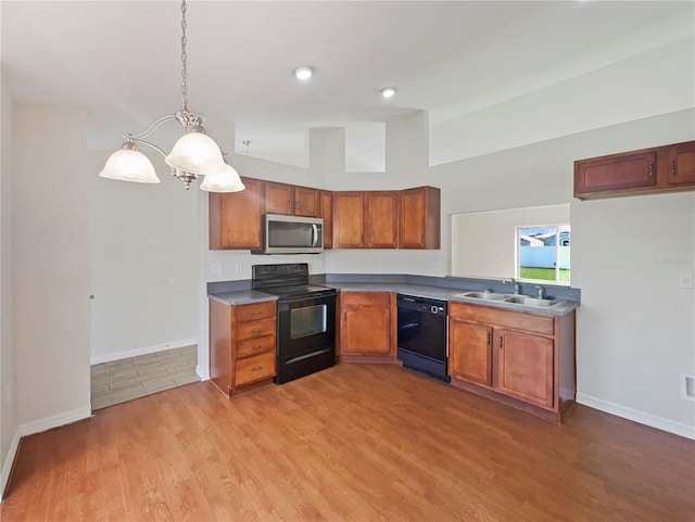 kitchen featuring sink, black appliances, light hardwood / wood-style flooring, and pendant lighting