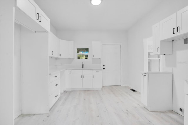 kitchen featuring sink, white cabinets, and light hardwood / wood-style flooring