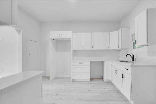 kitchen with white cabinetry, sink, and light wood-type flooring