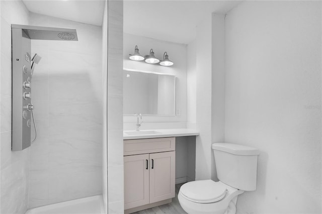 bathroom featuring vanity, tiled shower, and toilet