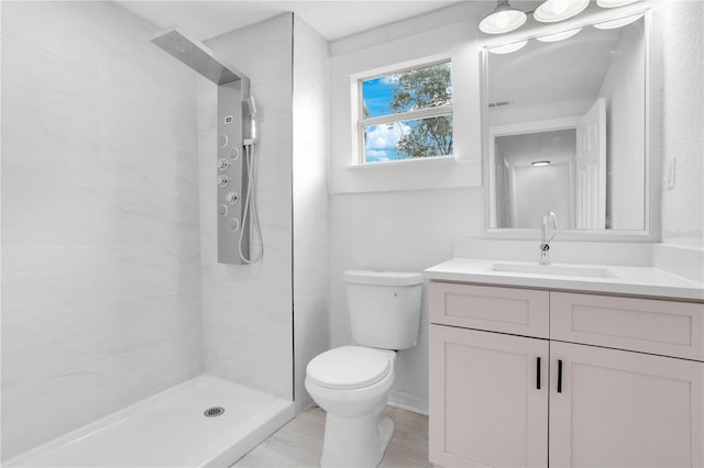 bathroom with vanity, toilet, and a tile shower