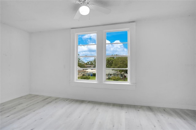 empty room featuring ceiling fan, light wood-type flooring, and a wealth of natural light