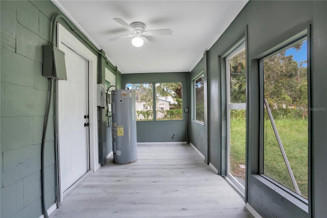 unfurnished sunroom featuring water heater, ceiling fan, and a wealth of natural light