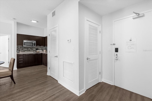 hall with a textured ceiling and dark hardwood / wood-style flooring