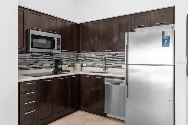 kitchen with sink, light tile patterned flooring, dark brown cabinetry, appliances with stainless steel finishes, and tasteful backsplash