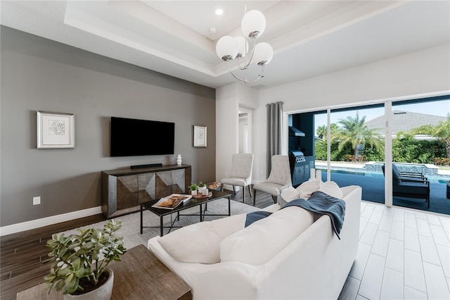 living room featuring light hardwood / wood-style floors, a chandelier, and a tray ceiling