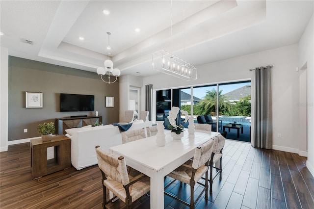 dining room featuring a notable chandelier, a tray ceiling, and dark hardwood / wood-style floors