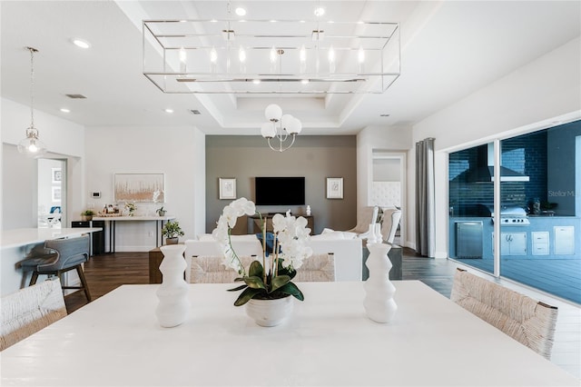 dining space with an inviting chandelier, a tray ceiling, and dark hardwood / wood-style flooring