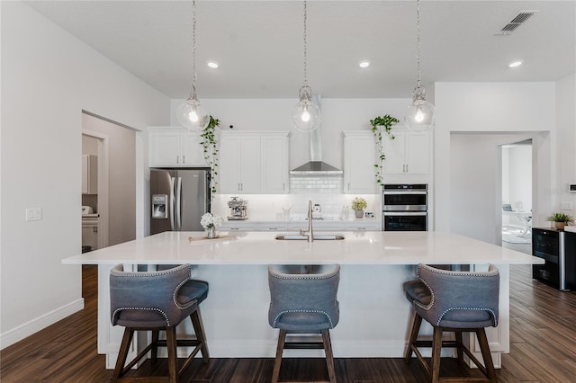 kitchen featuring a large island with sink, stainless steel appliances, and dark hardwood / wood-style floors