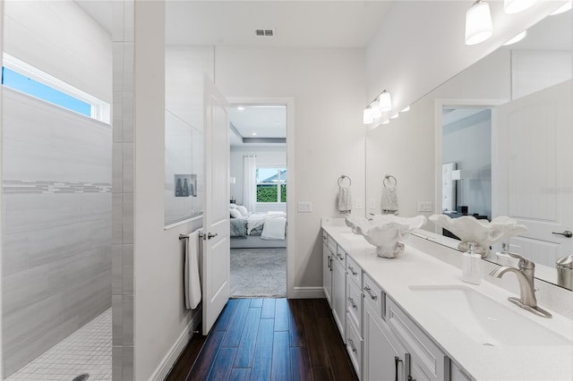 bathroom featuring vanity, wood-type flooring, plenty of natural light, and tiled shower