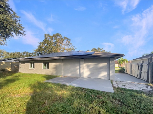 rear view of property with a patio, solar panels, and a lawn