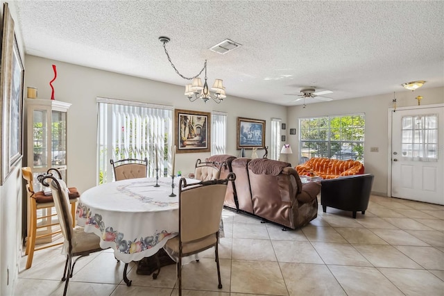 dining area featuring a textured ceiling, ceiling fan with notable chandelier, and light tile patterned floors