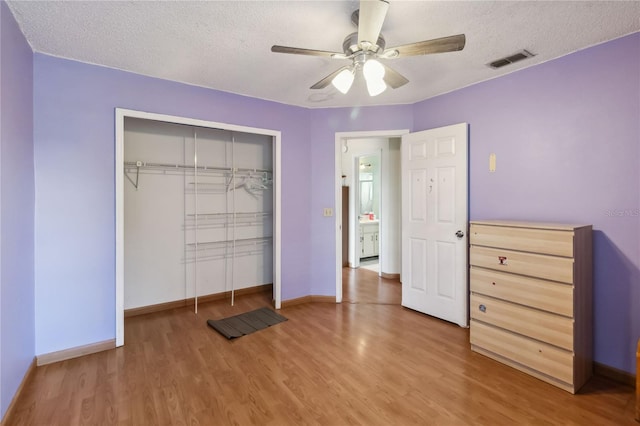 unfurnished bedroom featuring a textured ceiling, wood-type flooring, and ceiling fan