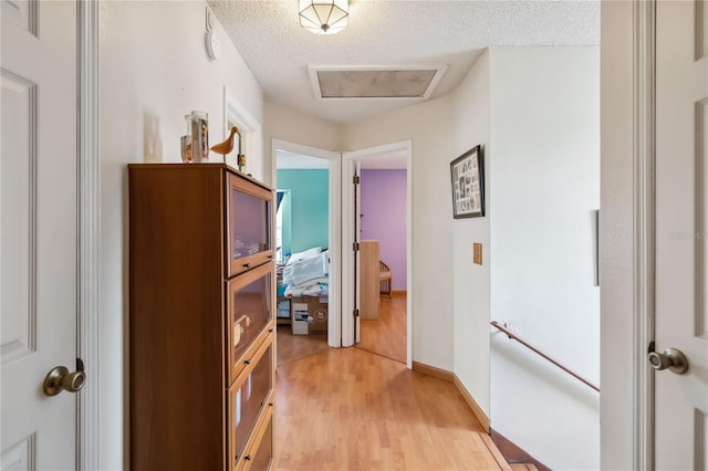 hall with light hardwood / wood-style flooring and a textured ceiling