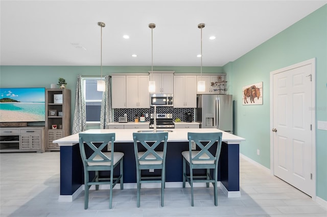 kitchen with a kitchen breakfast bar, pendant lighting, an island with sink, and stainless steel appliances