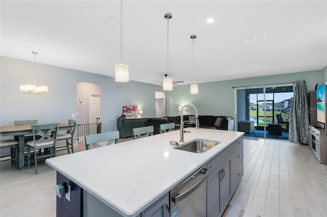 kitchen with dishwasher, sink, hanging light fixtures, and a center island with sink