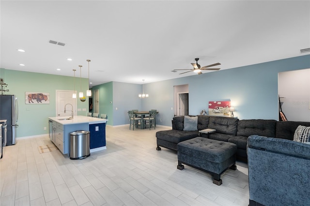 living room featuring ceiling fan, sink, and light wood-type flooring