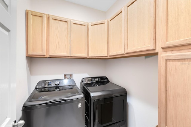 clothes washing area with washing machine and dryer and cabinets