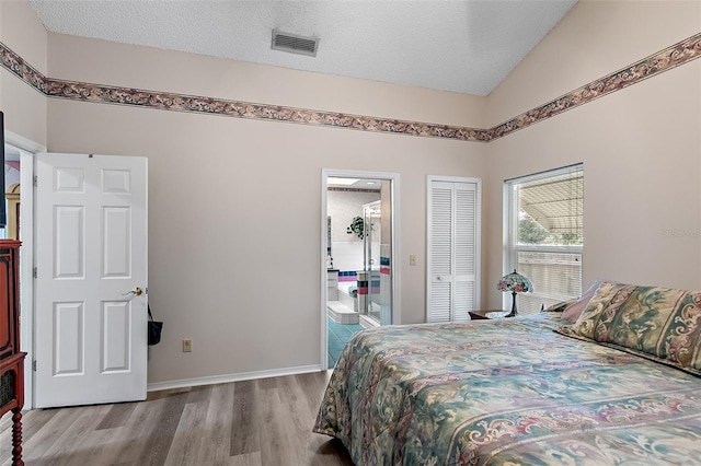 bedroom featuring a closet, a textured ceiling, light wood-type flooring, and vaulted ceiling