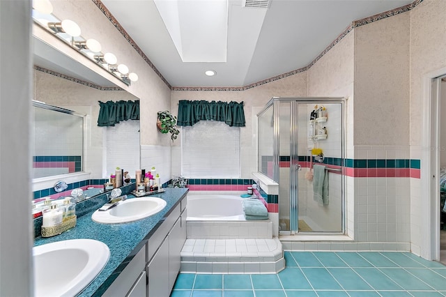 bathroom featuring vanity, separate shower and tub, a skylight, and tile patterned flooring