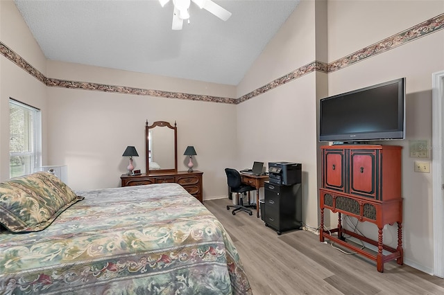 bedroom featuring lofted ceiling, a textured ceiling, light wood-type flooring, and ceiling fan