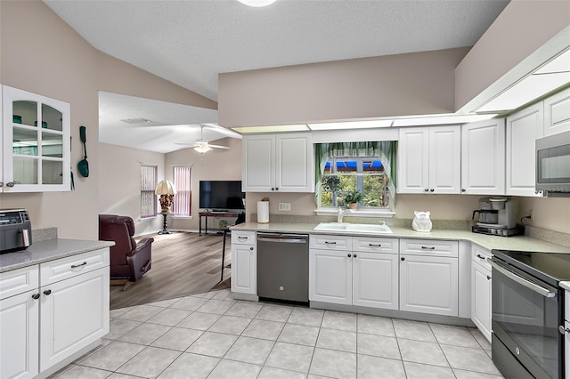 kitchen with sink, stainless steel appliances, lofted ceiling, and white cabinets