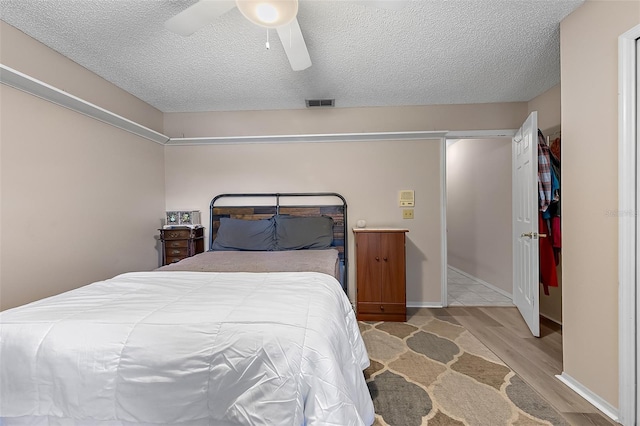 bedroom with a textured ceiling, light hardwood / wood-style floors, and ceiling fan