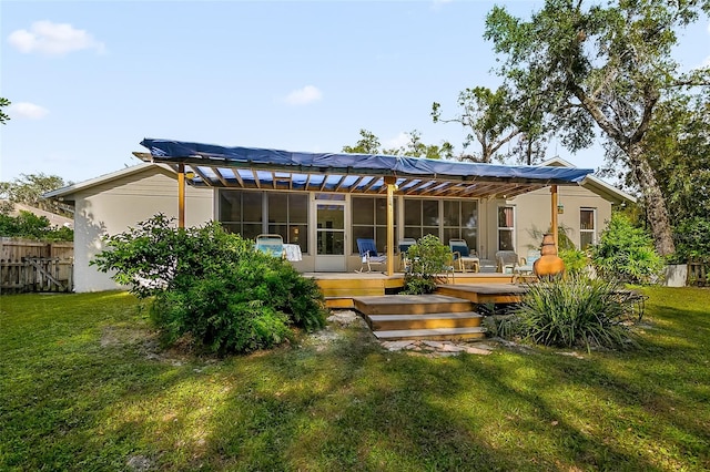 rear view of house with a yard, a deck, and a sunroom