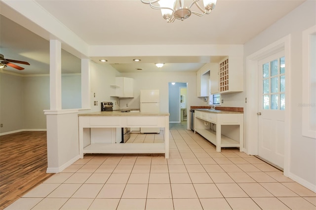 kitchen featuring kitchen peninsula, white cabinets, appliances with stainless steel finishes, light wood-type flooring, and ceiling fan with notable chandelier