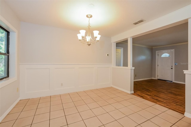 unfurnished room featuring light hardwood / wood-style flooring, a notable chandelier, and crown molding