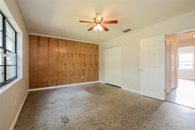 unfurnished bedroom with wooden walls and ceiling fan