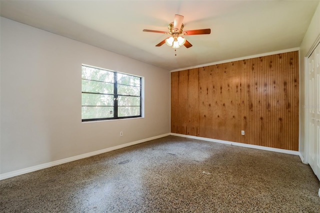 empty room featuring wood walls and ceiling fan