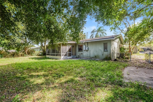 back of property with a yard, a sunroom, and a patio