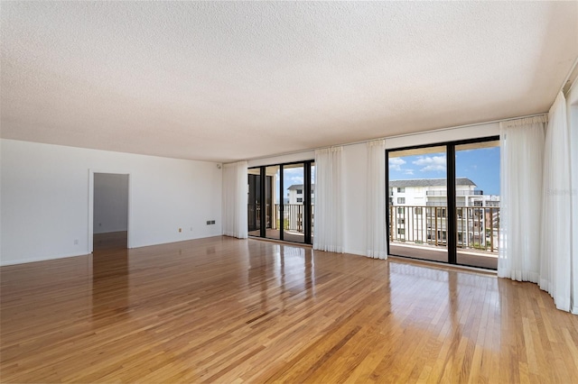 unfurnished room featuring light hardwood / wood-style floors, a textured ceiling, and floor to ceiling windows