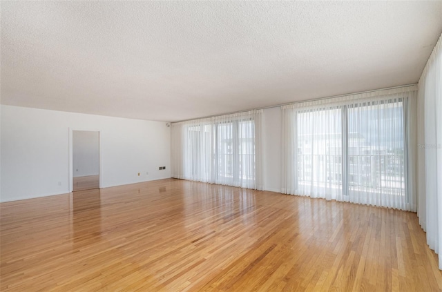 unfurnished room featuring light hardwood / wood-style flooring and a textured ceiling